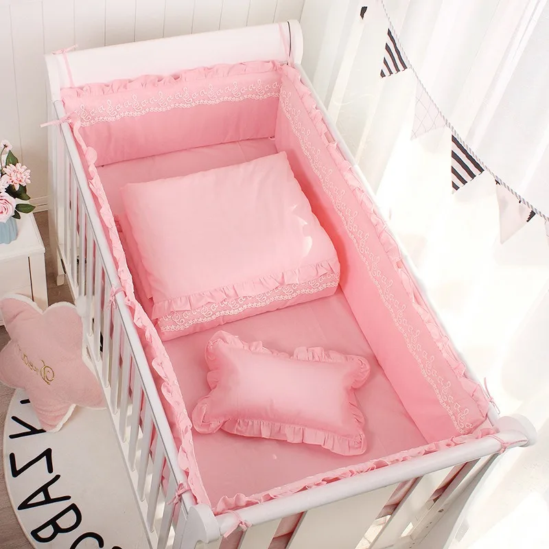 Berceau bébé lit à barreaux en bois structure métallique litière rose pastel coussins rembourrés motifs volant