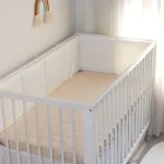 Lit bébé à barreaux design minimaliste en bois rembourré coussins côtés sécurité style moderne neutre chambre enfant 13 ans