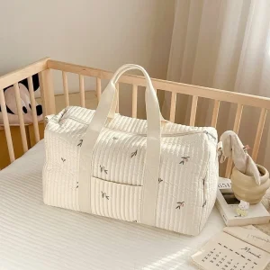 Sac de voyage pour maman sac maternité grande capacité design minimaliste style élégant poignées renforcées poche latérale texture matelassée couleur crème motifs brodés